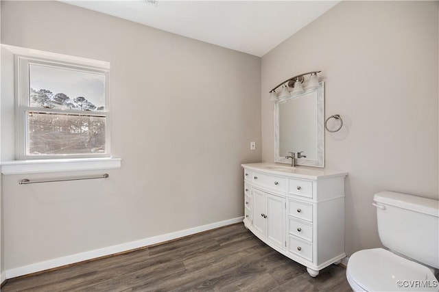 bathroom with vanity, wood finished floors, toilet, and baseboards