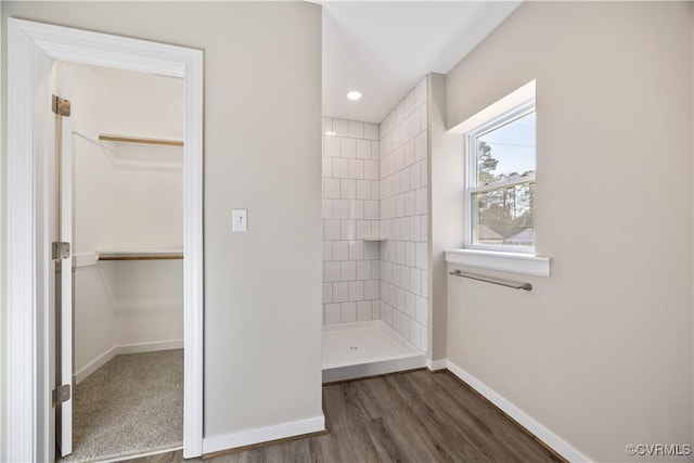 bathroom with recessed lighting, wood finished floors, baseboards, a spacious closet, and tiled shower