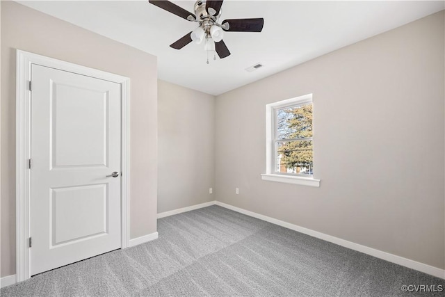 spare room with light carpet, baseboards, visible vents, and a ceiling fan