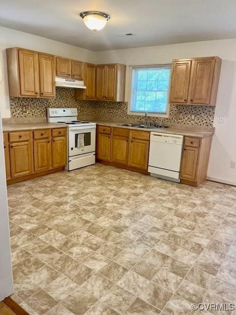 kitchen featuring light countertops, backsplash, a sink, white appliances, and under cabinet range hood