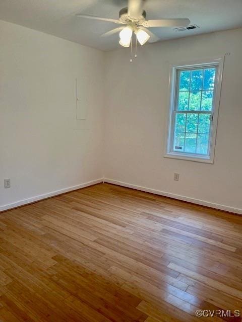 unfurnished room featuring baseboards, visible vents, ceiling fan, and wood finished floors