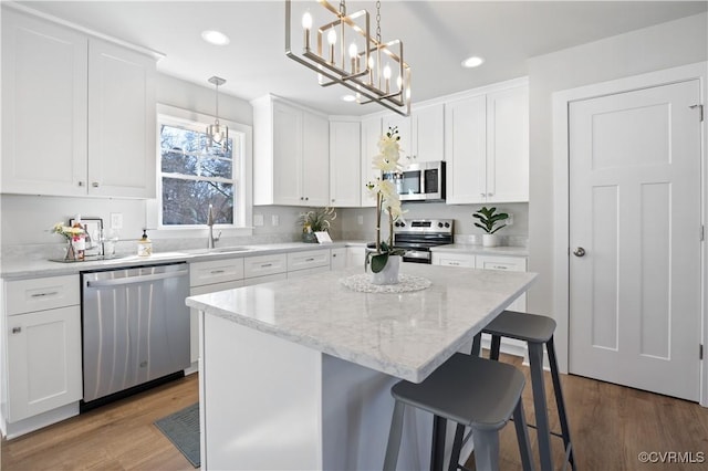 kitchen featuring stainless steel appliances, a breakfast bar, wood finished floors, and white cabinets