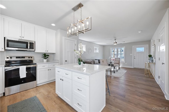 kitchen featuring a center island, stainless steel appliances, light wood-style flooring, open floor plan, and white cabinets