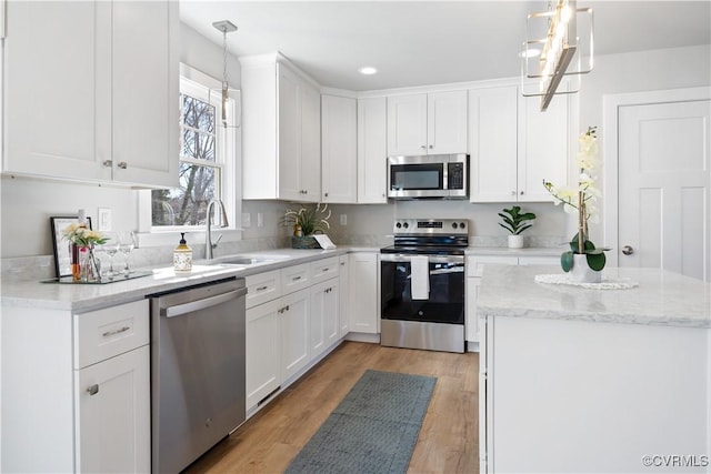 kitchen featuring appliances with stainless steel finishes, white cabinets, and a sink