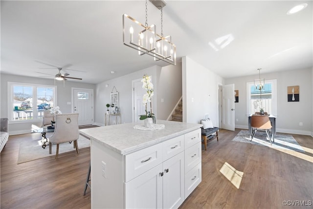 kitchen featuring baseboards, white cabinets, wood finished floors, a center island, and hanging light fixtures