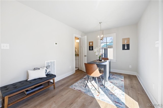 dining area with baseboards, visible vents, a chandelier, and wood finished floors