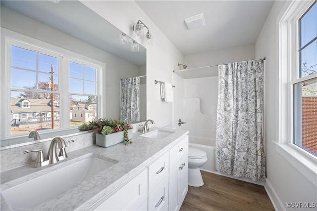 bathroom with toilet, shower / bathtub combination with curtain, a sink, and wood finished floors