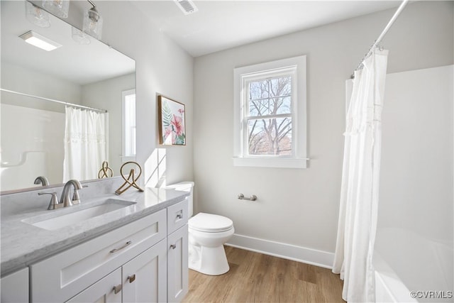 full bath with baseboards, visible vents, toilet, wood finished floors, and vanity