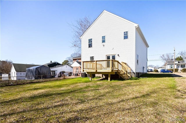 back of property with fence, a deck, and a yard