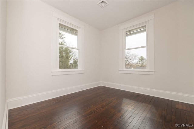 unfurnished room with dark wood-style floors, visible vents, plenty of natural light, and baseboards