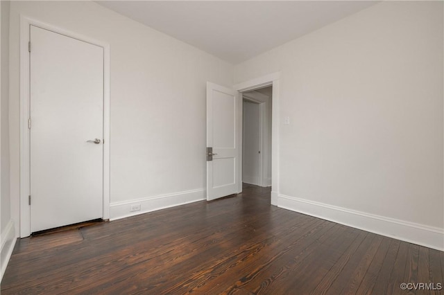 spare room featuring baseboards and dark wood-style flooring