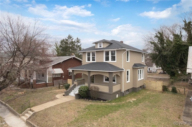 american foursquare style home featuring a porch, fence, a front lawn, and a shingled roof