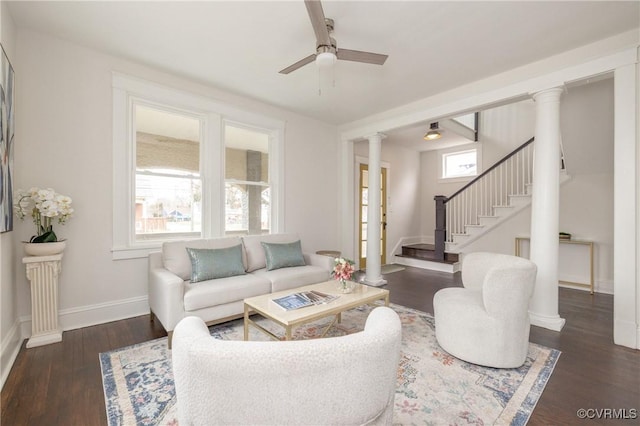 living area with wood finished floors, stairway, decorative columns, baseboards, and ceiling fan