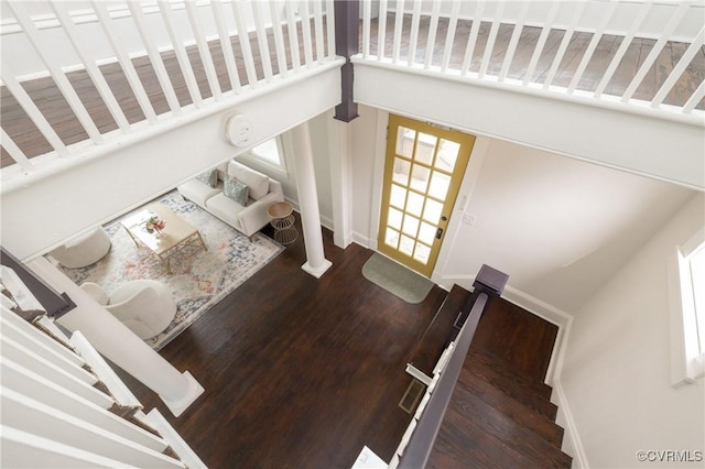 stairs with baseboards, wood finished floors, and a towering ceiling