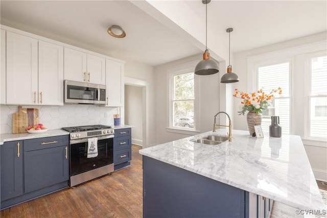 kitchen featuring tasteful backsplash, blue cabinetry, white cabinets, stainless steel appliances, and a sink