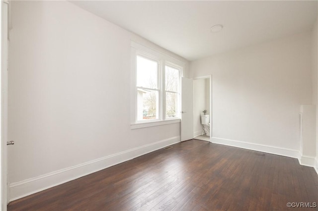 spare room featuring visible vents, baseboards, and dark wood-style flooring