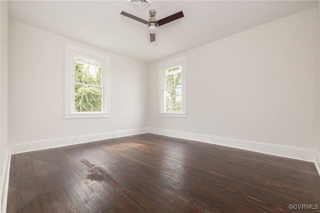 spare room with visible vents, a healthy amount of sunlight, dark wood-type flooring, and baseboards