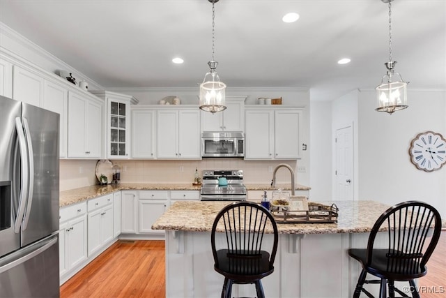 kitchen featuring stainless steel appliances, light wood-type flooring, white cabinetry, and backsplash