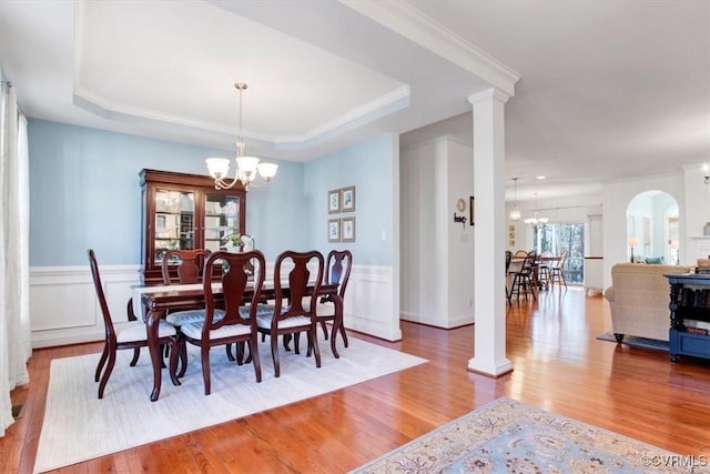 dining room with a tray ceiling, a notable chandelier, and wood finished floors