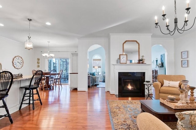 living area featuring ornamental molding, light wood finished floors, and a glass covered fireplace