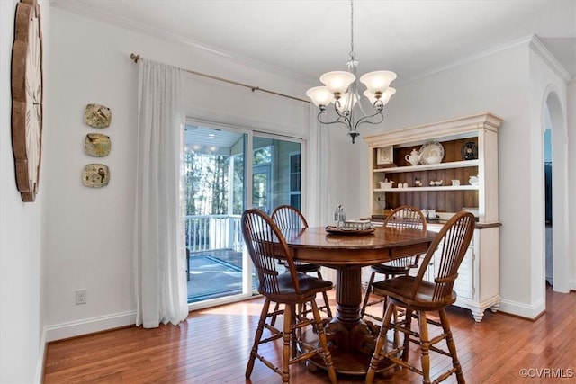 dining room featuring ornamental molding, arched walkways, wood-type flooring, and a notable chandelier