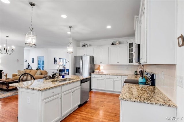 kitchen with stainless steel appliances, a sink, white cabinetry, backsplash, and light wood finished floors