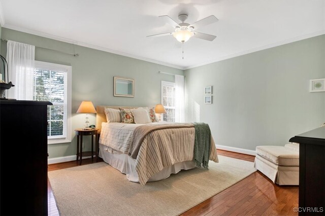 bedroom with wood-type flooring, baseboards, ceiling fan, and crown molding