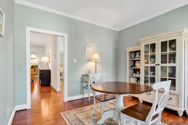 dining room featuring ornamental molding, wood finished floors, and baseboards