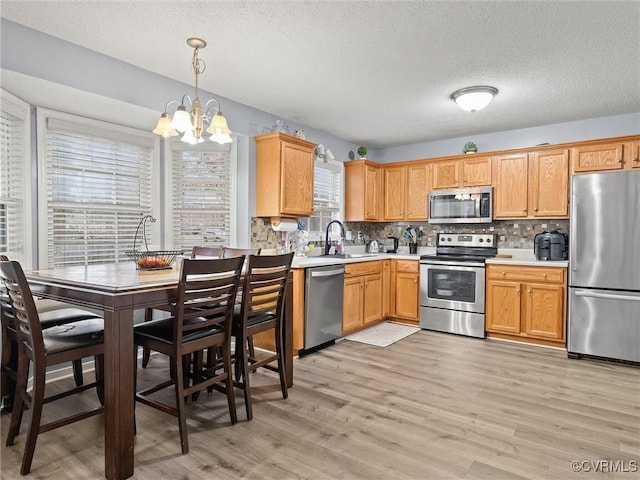 kitchen with light wood-style floors, appliances with stainless steel finishes, light countertops, and a sink