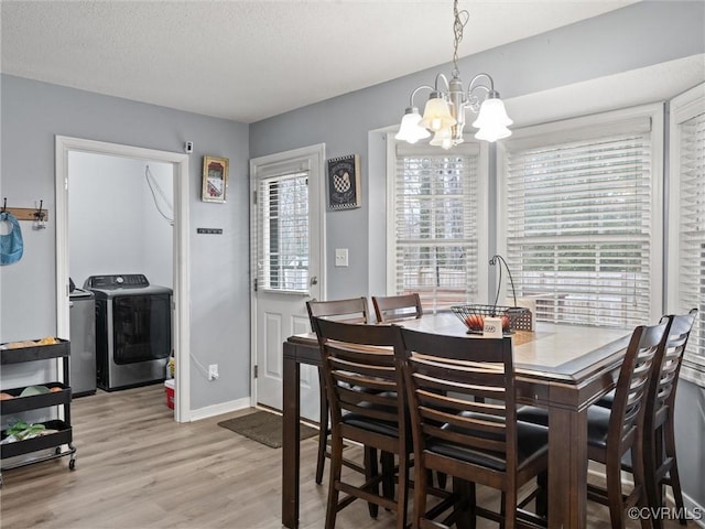 dining area with light wood-type flooring, a healthy amount of sunlight, a textured ceiling, and separate washer and dryer