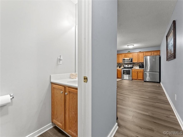 bathroom with a textured ceiling, tasteful backsplash, wood finished floors, and baseboards