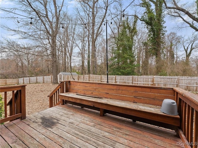 wooden deck with an outbuilding, a storage unit, and a fenced backyard