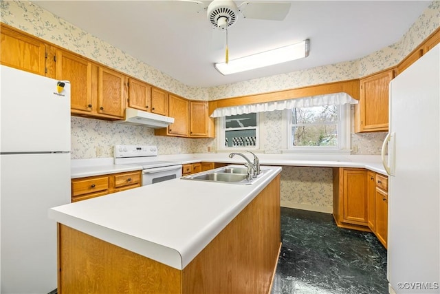 kitchen featuring under cabinet range hood, white appliances, wallpapered walls, and a sink