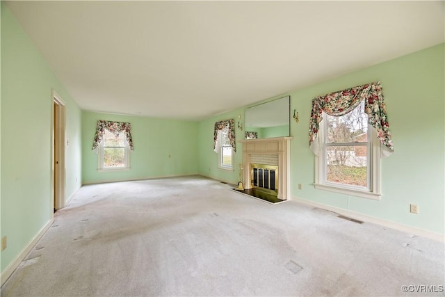 unfurnished living room featuring a glass covered fireplace, visible vents, baseboards, and carpet