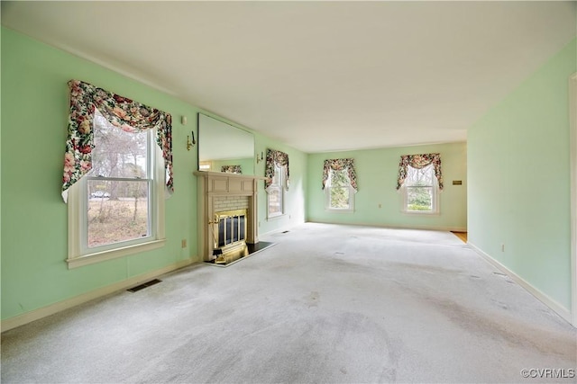 unfurnished living room featuring visible vents, carpet floors, baseboards, and a glass covered fireplace