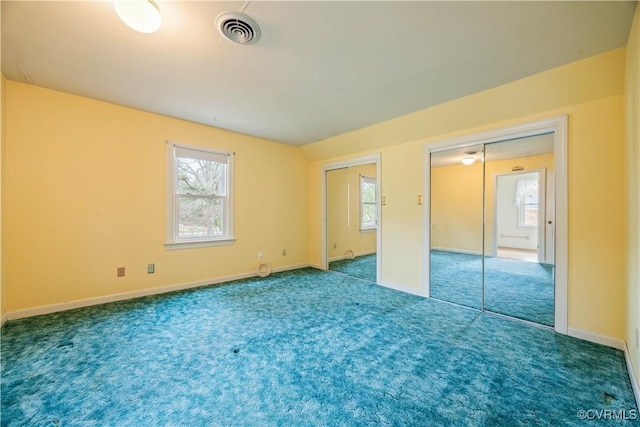 unfurnished bedroom with two closets, visible vents, multiple windows, and carpet