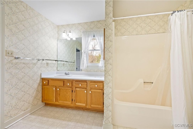 bathroom with wallpapered walls, vanity, shower / bath combo with shower curtain, and baseboards