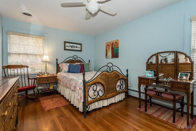 bedroom with visible vents, baseboard heating, and wood finished floors