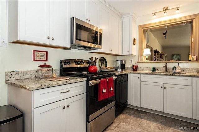 kitchen with appliances with stainless steel finishes, white cabinetry, a sink, and light stone countertops