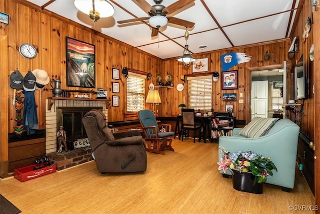 living area with wooden walls, ceiling fan, a fireplace, and wood finished floors