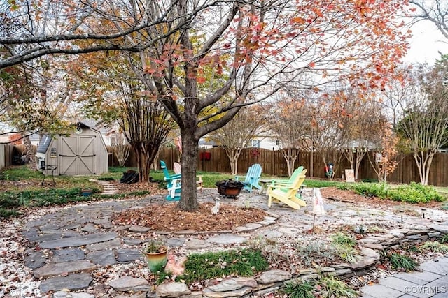 view of yard with a fire pit, a shed, an outdoor structure, and a fenced backyard