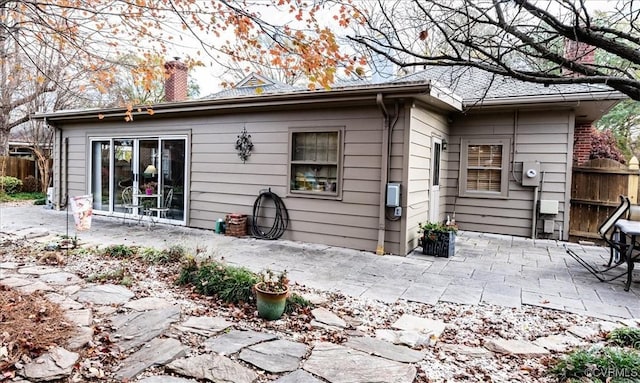 rear view of property with a patio, a chimney, and fence