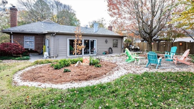 rear view of house featuring an outdoor fire pit, a patio area, fence, and a chimney