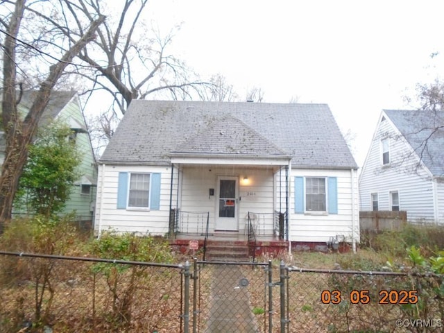 view of front of house featuring a porch, a fenced front yard, a shingled roof, and a gate