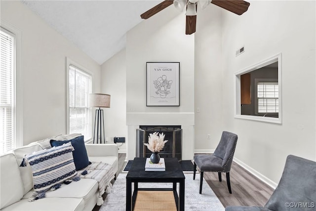 interior space featuring high vaulted ceiling, a fireplace, wood finished floors, visible vents, and baseboards