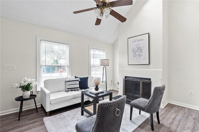 living area with baseboards, a ceiling fan, wood finished floors, vaulted ceiling, and a fireplace