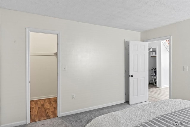 bedroom with carpet, baseboards, a walk in closet, and a closet