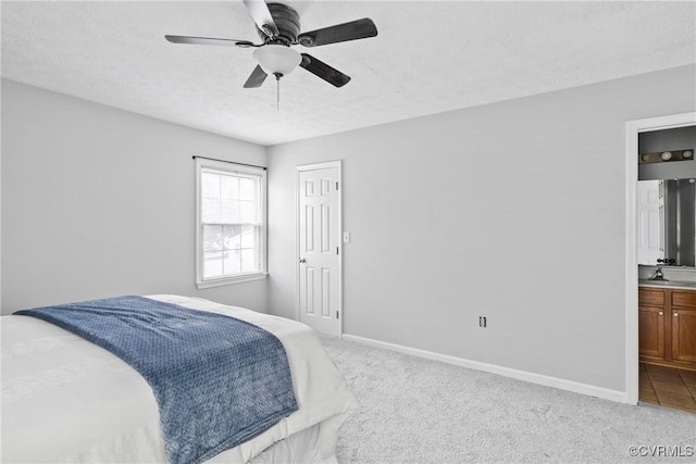 bedroom featuring light carpet, baseboards, connected bathroom, a textured ceiling, and a sink