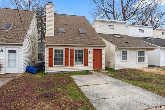 view of front of property featuring a front yard, roof with shingles, and a chimney