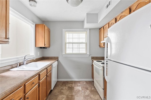 kitchen featuring visible vents, a sink, white appliances, under cabinet range hood, and baseboards